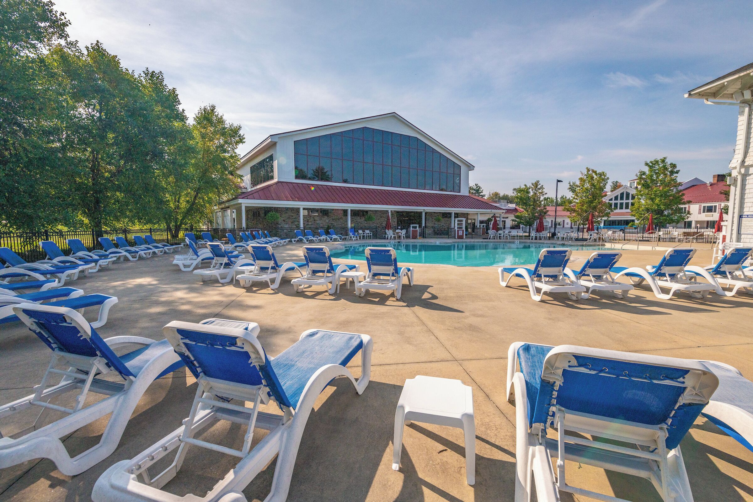 Un espace piscine avec des chaises longues et un bâtiment doté de grandes fenêtres.