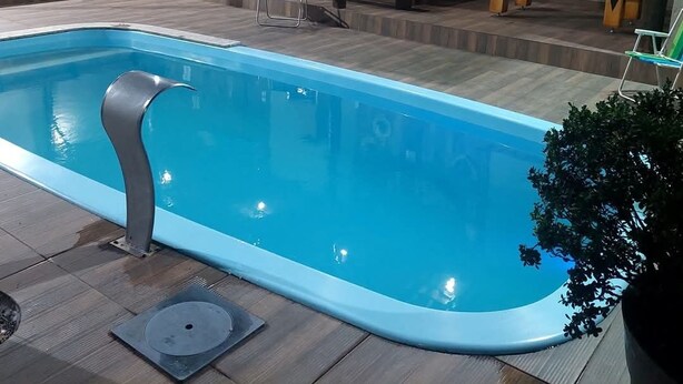 En swimmingpool med en træterrasse, omgivet af træmøbler og et rustikt interiør.