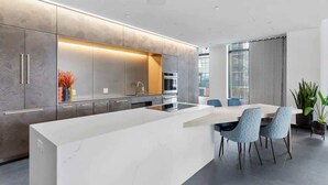 A modern kitchen with a central island, built-in appliances, and a dining area with chairs. - Luxury Apartment w King Bed, Shared Pool & Rooftop (Cambridge)