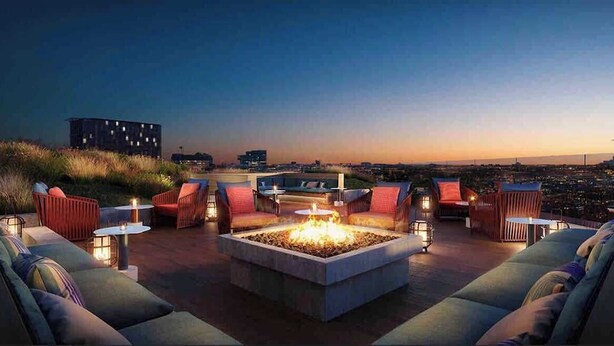 A rooftop lounge with a fire pit, seating, and city views at dusk. - Luxury Apartment w King Bed, Shared Pool & Rooftop (Cambridge)