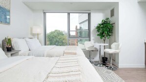 Een moderne hotelkamer met een groot raam, een bed, een bureau, twee stoelen en een potplant.