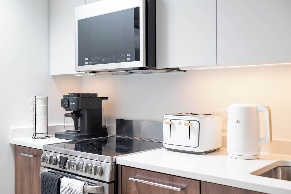 Eine moderne Küche mit integriertem Mikrowellenherd, Kaffeemaschine, Toaster, Wasserkocher und Herd.