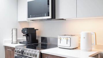 Eine moderne Küche mit integriertem Mikrowellenherd, Kaffeemaschine, Toaster, Wasserkocher und Herd.