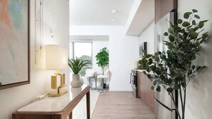 A modern kitchen with a wooden countertop, a potted plant, and a dining area with a white chair and table. - Luxury Studio with King bed Gym near MIT Harvard in Central Square! (Cambridge)