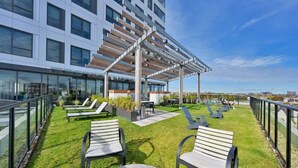 A rooftop terrace with outdoor seating, a pergola, and a view of the city skyline. - Upscale 1BR MIT Harvard WiFi Gym W D Parking! (Cambridge)