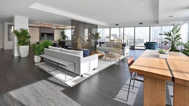A spacious, modern living area with a large sofa, a wooden dining table, and a city view. - Upscale 1BR MIT Harvard WiFi Gym W D Parking! (Cambridge)