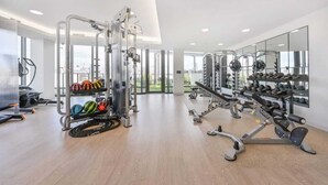 Ein modernes Fitnessstudio mit Cardiogeräten, Krafttrainingsgeräten und einer Hantelbank.