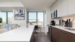 Eine moderne Küche mit einer großen Kochinsel, Edelstahlgeräten und Blick auf die Stadt.