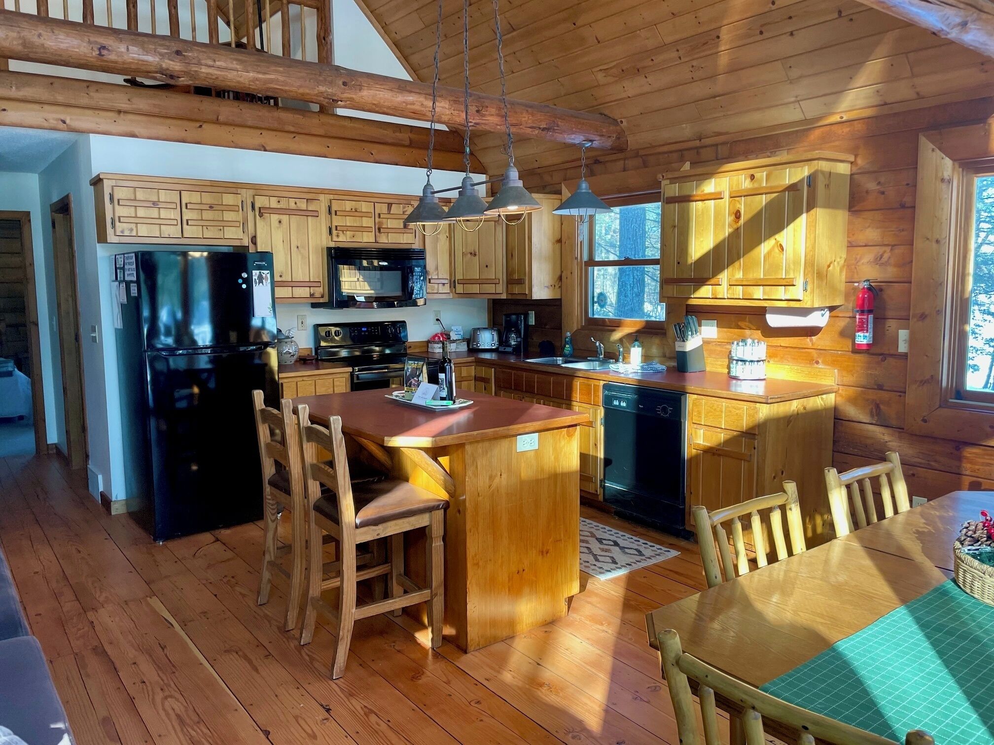 A wooden cabin kitchen with a central island, wooden cabinets, a refrigerator, a microwave, and a dishwasher.