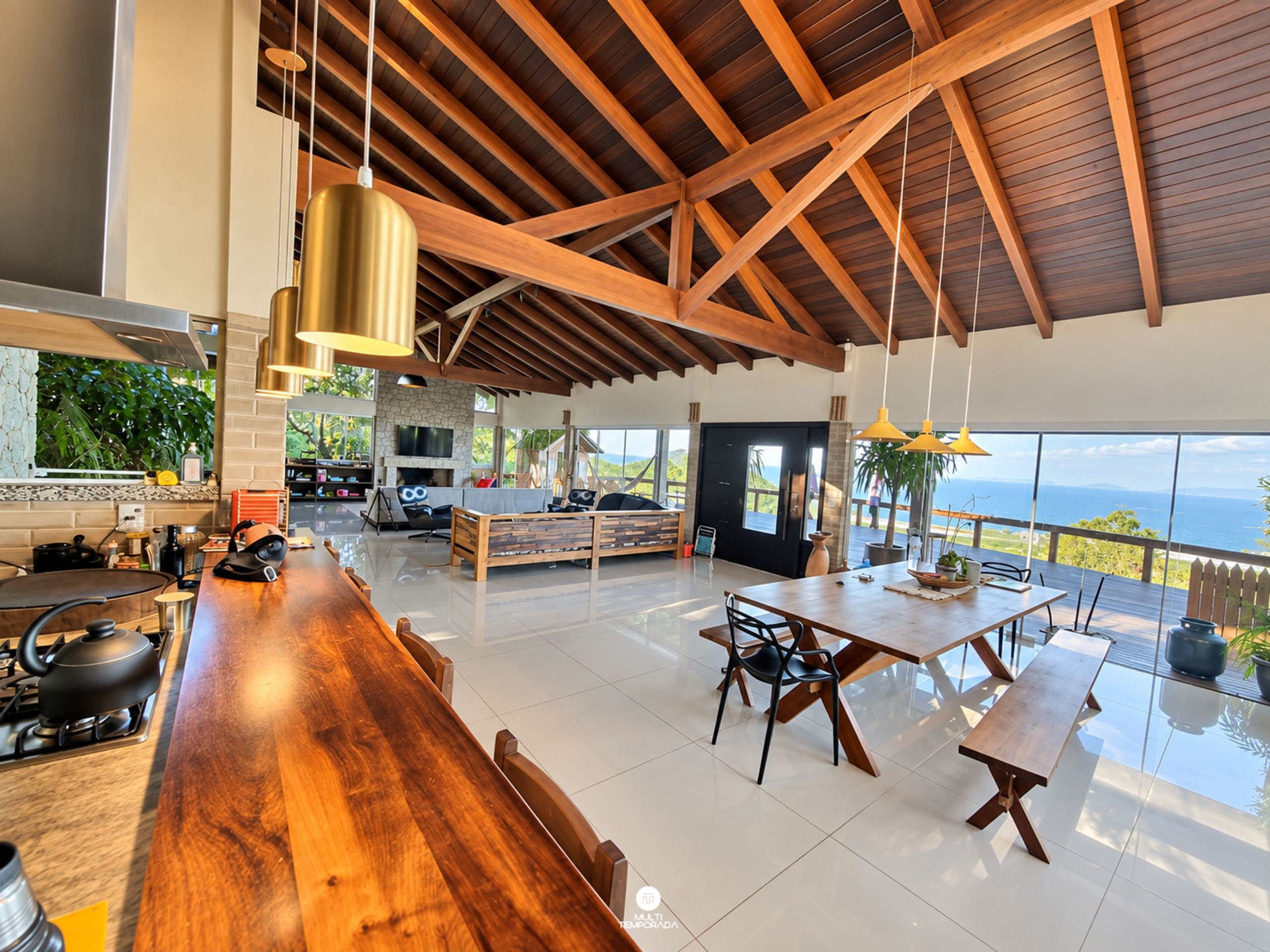 A spacious living area with a high ceiling, a dining table, and a view of the ocean.