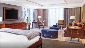 Ein Hotelzimmer mit Bett, Schreibtisch, Sessel, Sofa und Fernseher.