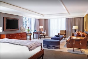 Una habitación de hotel con cama, escritorio, silla, sofá y televisor.