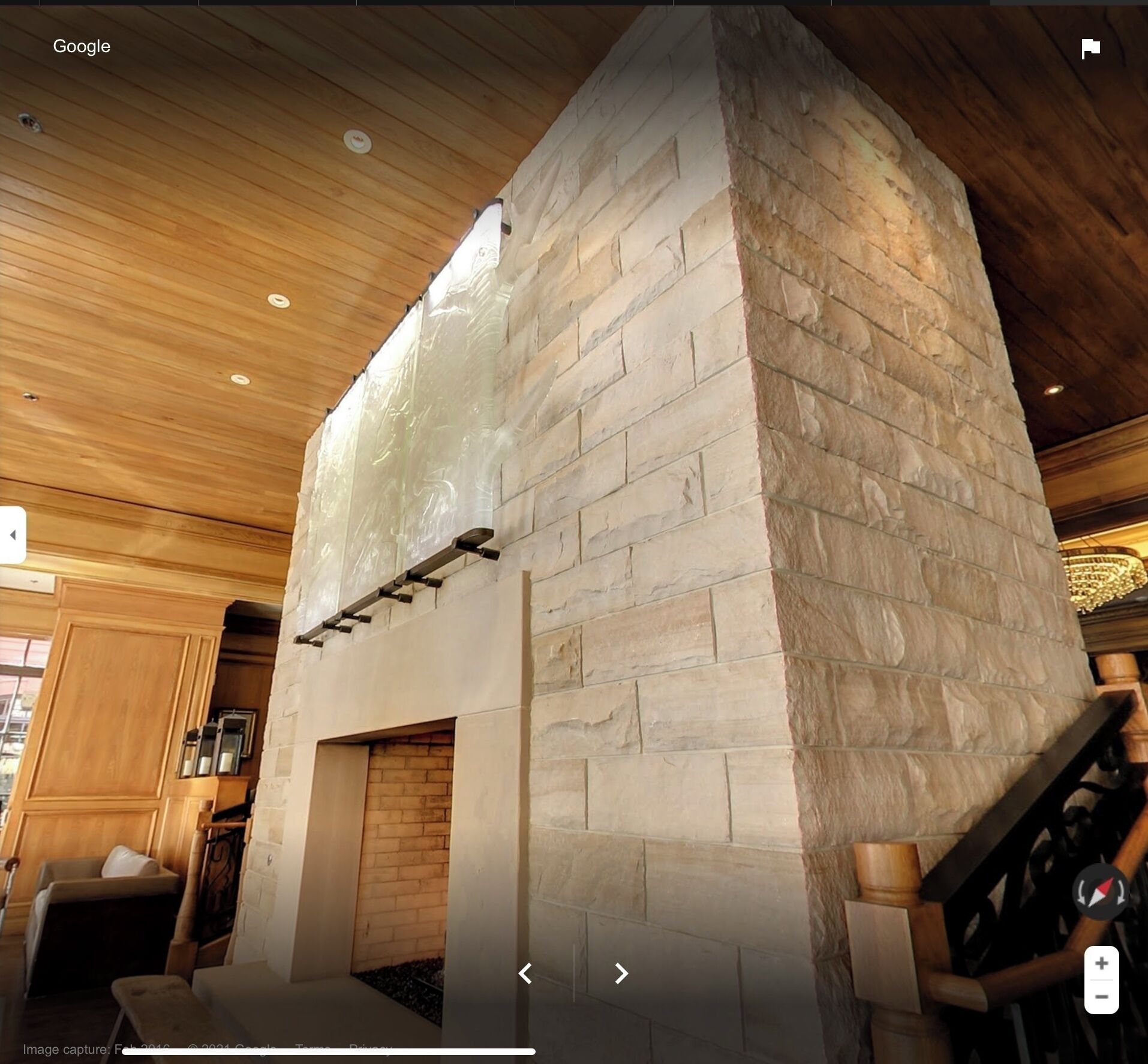 Un intérieur moderne agrémenté d’une cheminée en pierre, d’un plafond en bois et de sièges intégrés.