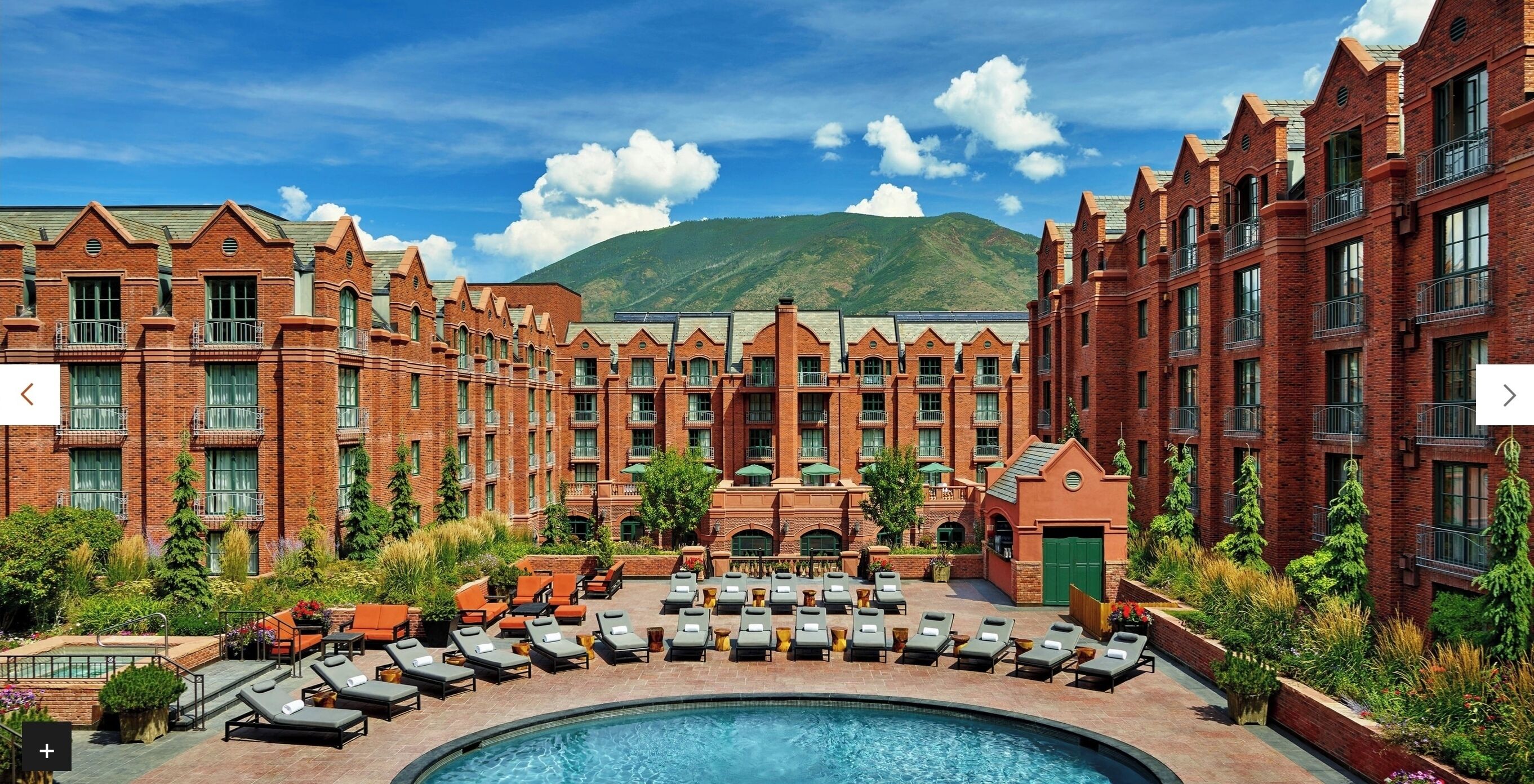 Un hôtel doté d’une piscine, de nombreuses chaises longues et offrant une vue sur les montagnes.