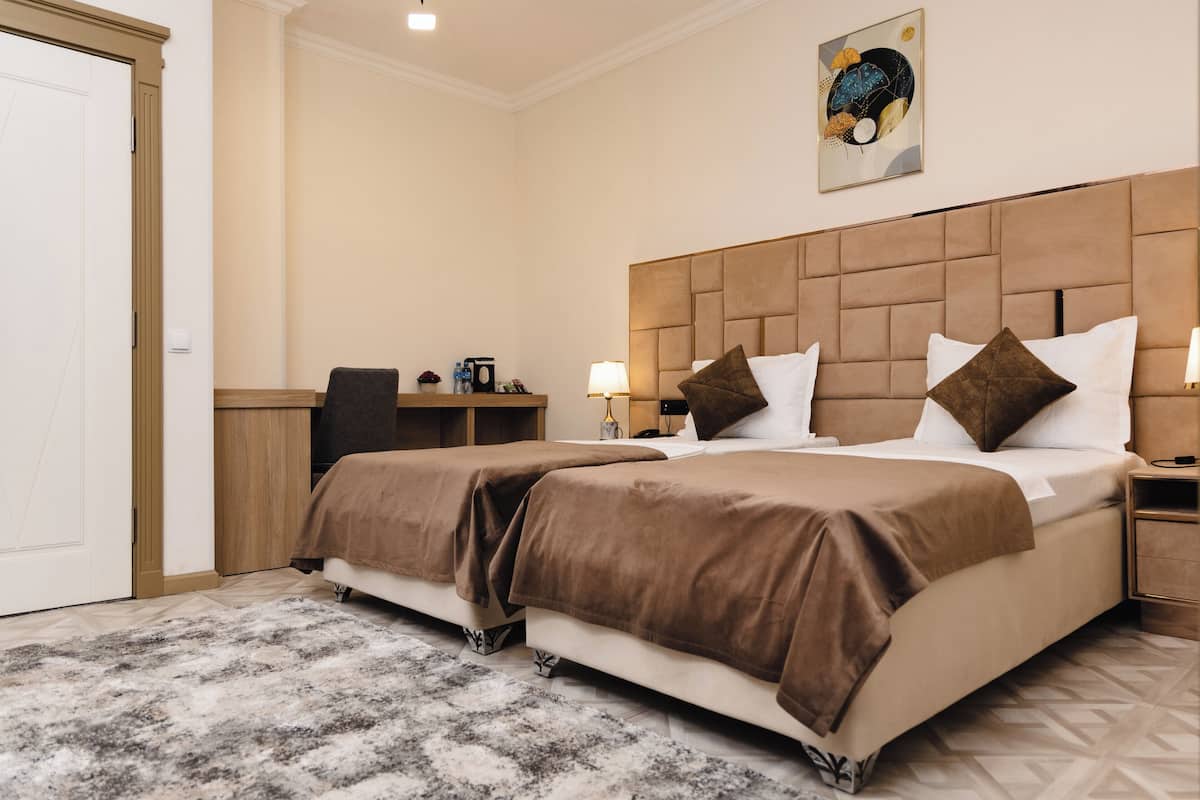 A hotel room with a large bed, two bedside tables, a desk, and a chair.