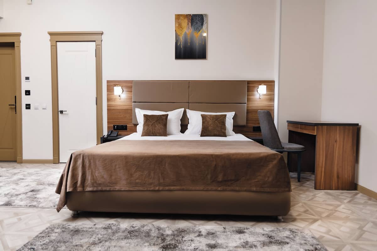 A hotel room with a large bed, a desk, and a chair.