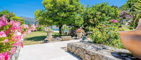 Un sendero en el jardín que conduce a un muro de piedra con una jardinera grande a la derecha.
