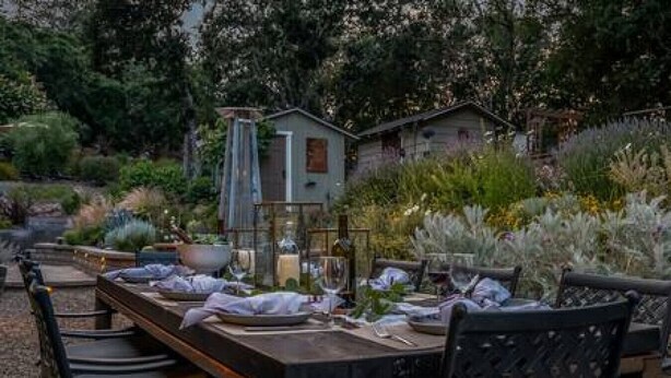 An outdoor dining area with a long wooden table set for a meal, surrounded by chairs. - Vineyard Haven: Pool, Hot Tub & Wine Country Charm (Kenwood)