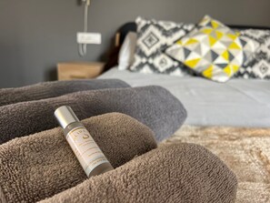 Ett hotellrum med en säng, kuddar och en flaska placerad på en mönstrad, brun matta.