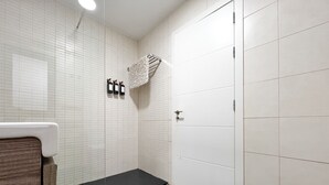 Een moderne badkamer met witte betegelde wanden, een douche en een toilet.