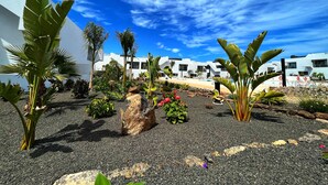 Een modern resort met witte gebouwen, een zwembad en tropische beplanting.