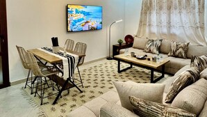 Un salon comprenant un canapé, une table basse, un téléviseur et un coin repas avec des chaises et une table.
