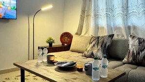 Un salon avec un canapé, une table basse, un téléviseur et une lampe.