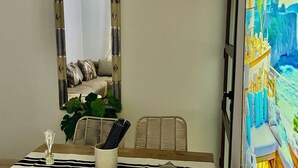 Un espace repas comprenant une table, des chaises, une horloge, un miroir et un tableau.