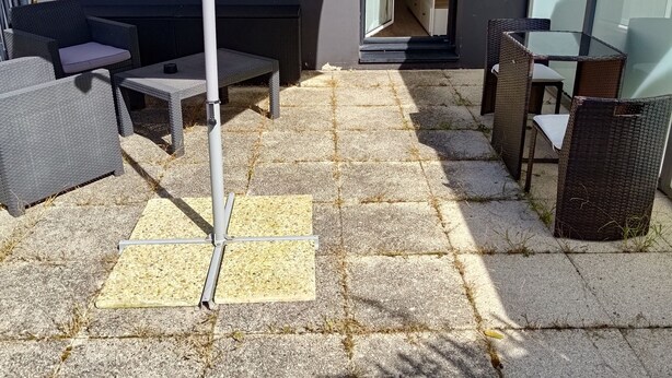 Een terras met buitenmeubilair, een pergola en een uitzicht op het interieur door een glazen deur.
