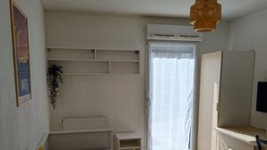 Een slaapkamer met een bed, een bureau en een radiator.