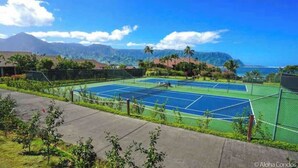 Un court de tennis offrant une vue sur l’océan et les montagnes.