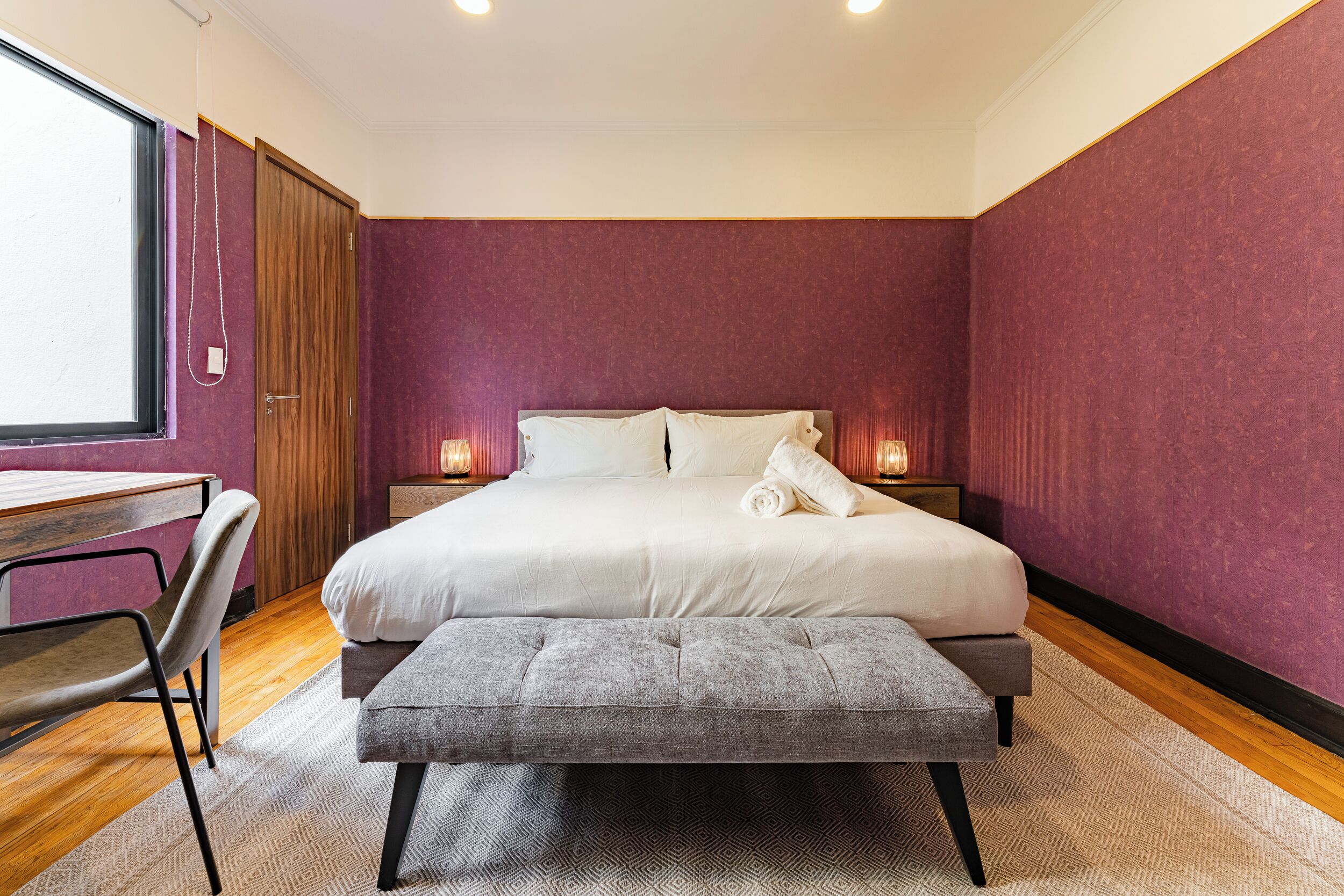 Une chambre à coucher avec un lit, des tables de chevet, un bureau et une chaise.