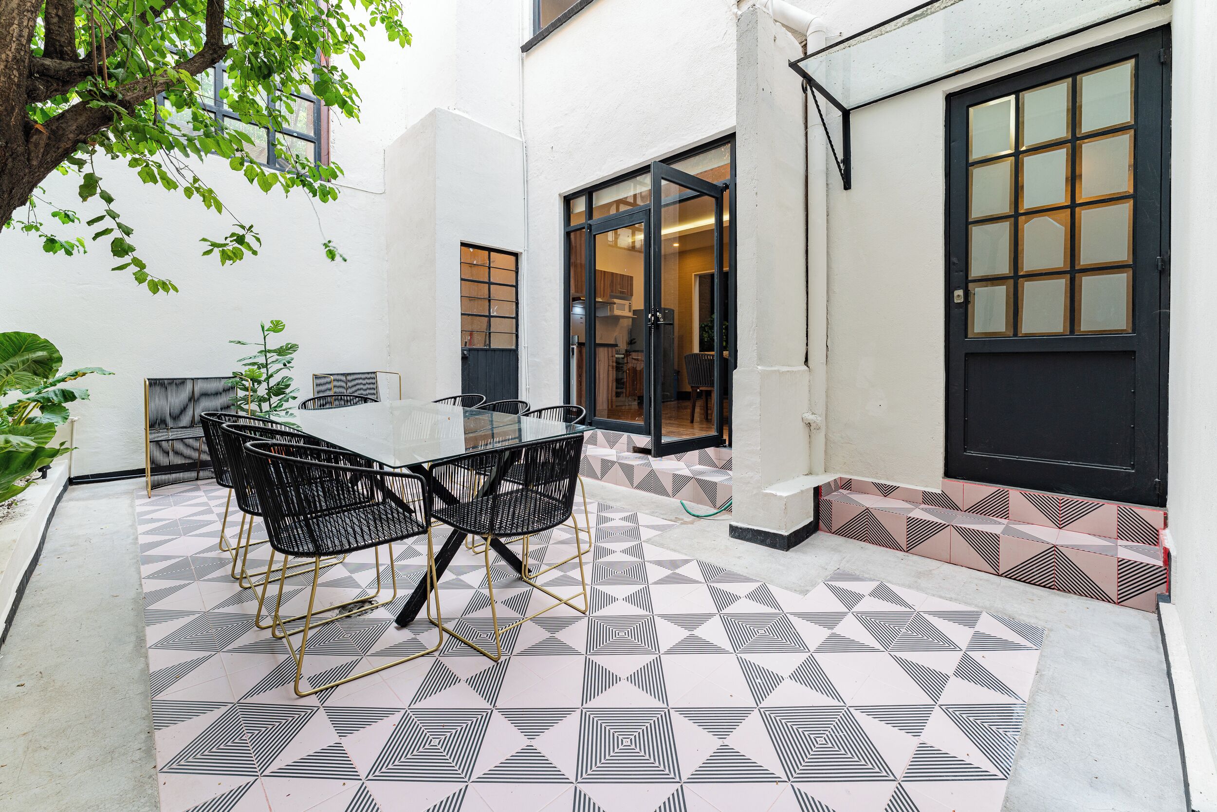 A patio with a table and chairs, a tiled floor, and a door leading to a kitchen.
