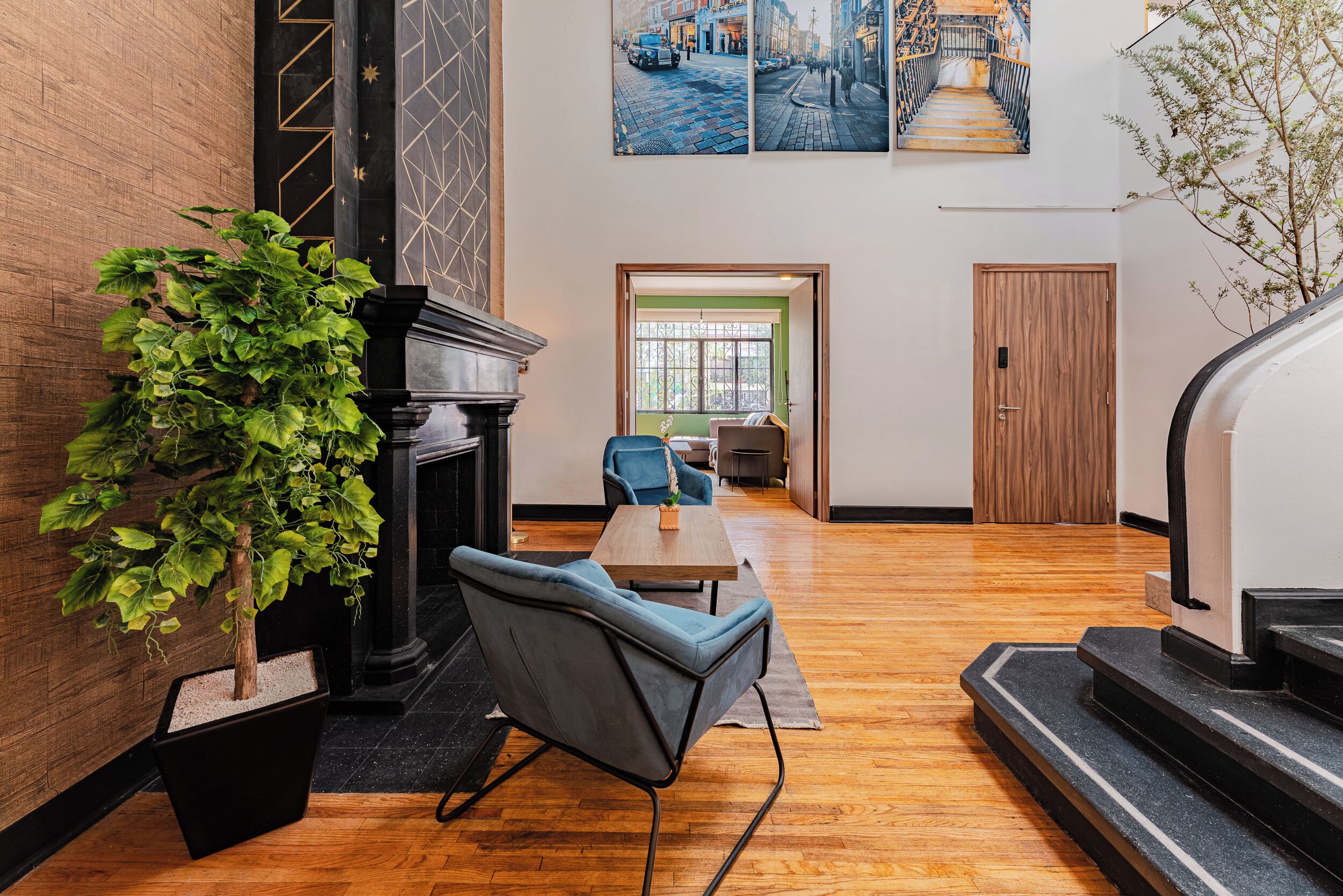 A spacious lobby with a fireplace, a seating area with chairs, a large potted plant, and a staircase.