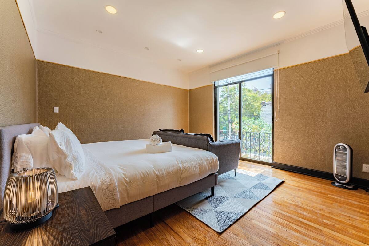 Een moderne hotelkamer met een groot bed, een bank, een elektrische kachel en uitzicht op het omliggende landschap.