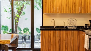 Una cocina con armarios de madera, encimera negra y ventana con vistas a la vegetación.