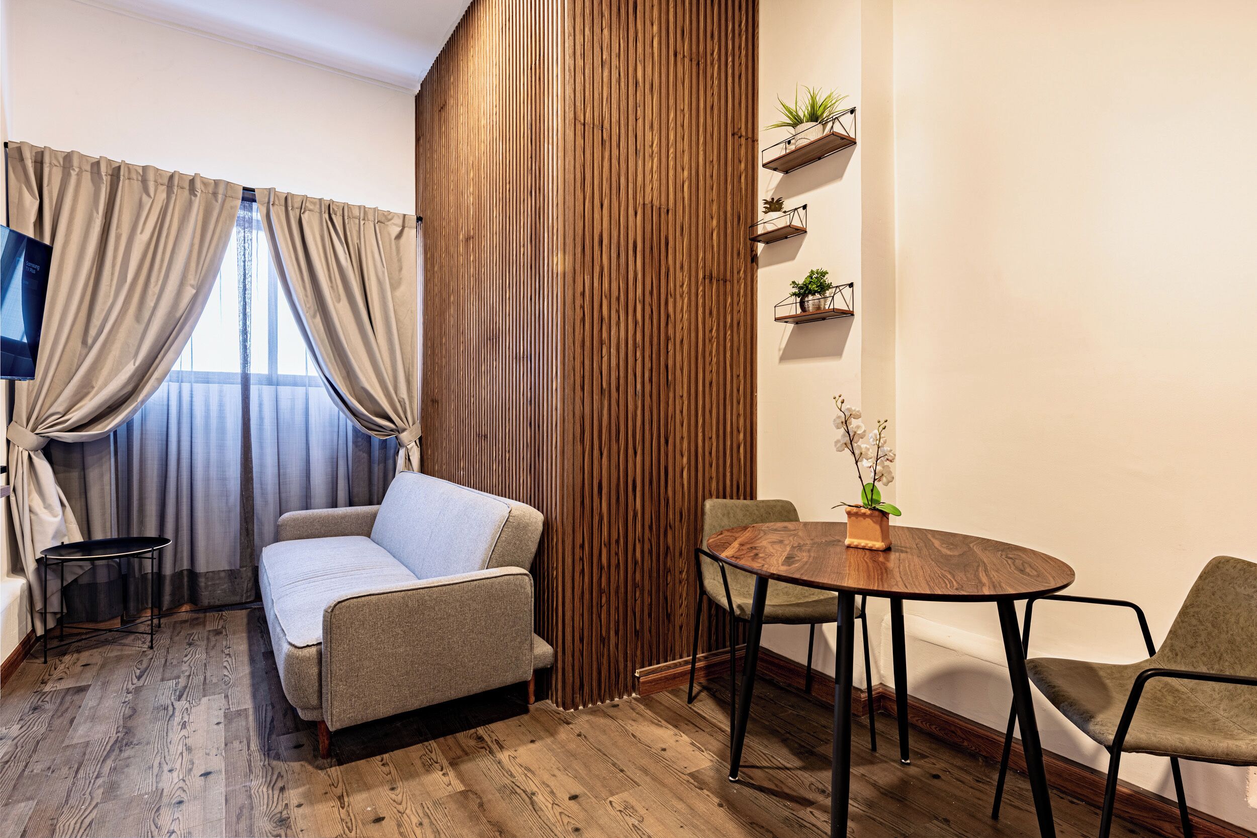 Une pièce moderne comprenant un canapé, une table à manger avec des chaises, un téléviseur et un lambris en bois.