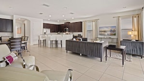 A modern living area with a kitchen, dining space, and seating. - 5BR Spacious Villa • Pool, Spa • Near Disney (Kissimmee)