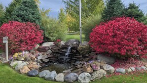 A garden with a small waterfall, surrounded by rocks and colorful bushes.