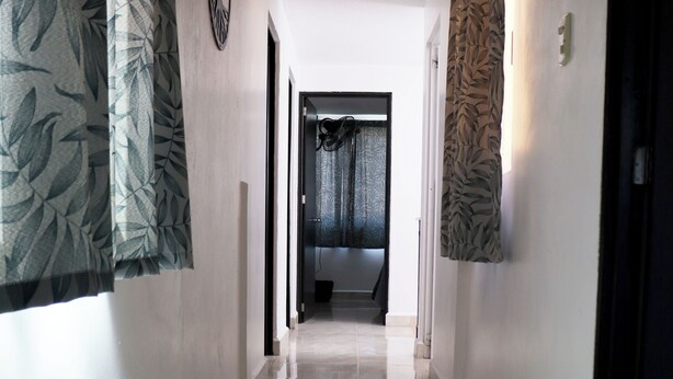 A hallway with a tiled floor, patterned curtains, and a door at the end. - Casa Benavente (Tehuacán)