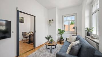 Ein modernes Wohnzimmer mit einer grauen Couch, einem runden Couchtisch und einem Essbereich mit Tisch und Stühlen.
