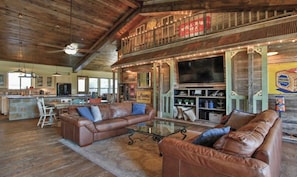 A rustic interior with leather sofas, a glass coffee table, and a bar area with vintage decor. - Lazy River Retreat in northwest Houston (Cypress)