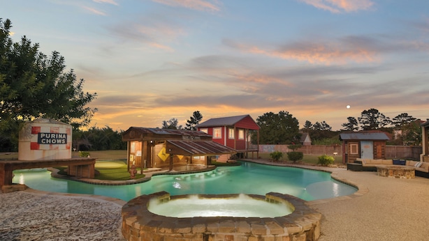 Une piscine avec un jacuzzi, un bâtiment rouge et une enseigne sur laquelle on peut lire « PURINA CHOWS ».