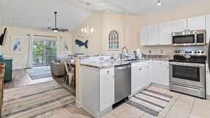 A modern kitchen with white cabinets, stainless steel appliances, and a large island.
