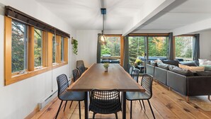 A modern dining area with a wooden table, black chairs, and a sofa.