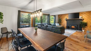 A modern dining area with a wooden table and chairs, a sofa, and a fireplace.