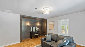 Un salon moderne avec un canapé gris, un plancher en bois et un mur d’accent en pierre.