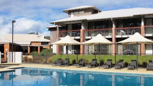A hotel with a swimming pool, sun loungers, and umbrellas.