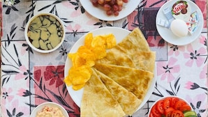 A table with a variety of food items including grapes, chips, a bowl of soup, a plate of sliced tomatoes and cucumbers, and a glass of a white beverage. - Park Plaza hotel (Cairo)
