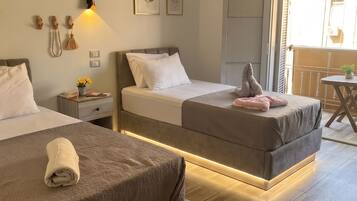 A hotel room with two beds, a bedside table, a wall-mounted light, and a view of the outside.